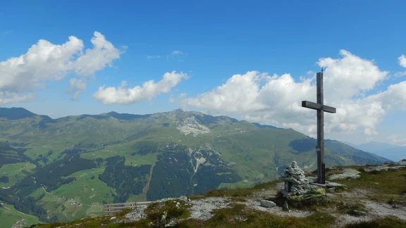 Gipfelkreuz Tettensjoch Holzkreuz am Gipfel des Tettensjochs in Tux/Zillertal, im Hintergrund grüne Bergrücken und felsige Gipfel.