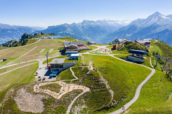 Bergstation Penkenjoch Luftaufnahme der Bergstation Penkenjoch im Zillertal: Almwiesen, geschwungene Wege, Hütten, dahinter die Berge.