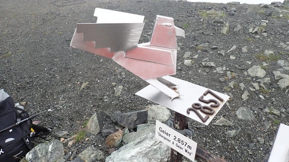 Gipfelschild Geier Gipfelschild am Geier in Tux mit Höhenangabe und Richtungspfeil, aufgestellt auf einem Steinhaufen im Geröll.